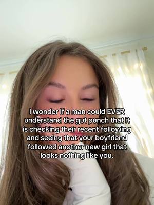 A close-up of a young woman with long, wavy brown hair. She has a pale complexion with subtle pink makeup on her eyelids. Her eyes are closed, and she appears to be deep in thought or conveying a sense of emotion. Overlaid on the image is white text detailing a relationship scenario. The background is softly blurred, with hints of a light-colored wall and window visible.