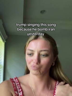 A young woman with blonde hair is looking towards the camera with a slightly pursed expression. She's wearing a red and white patterned top and a necklace. The background is blurry, suggesting an indoor setting with a window visible. Text overlay is presented on top.