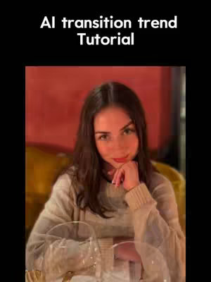 A young woman is posing indoors. She wears a light-colored sweater and rests her chin on her hand. In the background, a soft, warm red and gold color scheme creates a backdrop for the subject with some wine glasses.