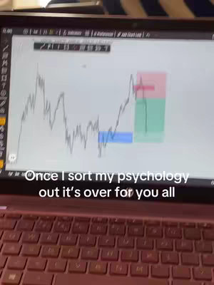 A laptop displays a financial graph on its screen. Below the screen is the keyboard, viewed at a slight downward angle. The background shows a blurry view of the surroundings.