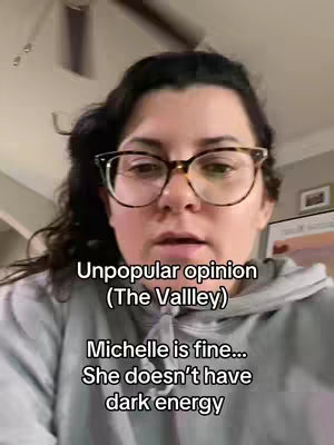A woman with dark curly hair and glasses is centered in the frame, against a blurred background. Text overlays on the image present thoughts on 'The Valley' and a commentary on a cast member.