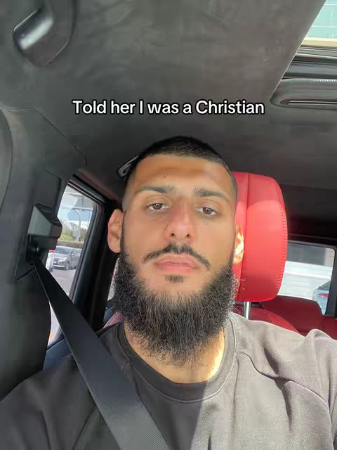 A man with a beard is sitting in a car. The man is wearing a black shirt, and the seat is red. The car has a sunroof open. Text is overlaid on the cover image.
