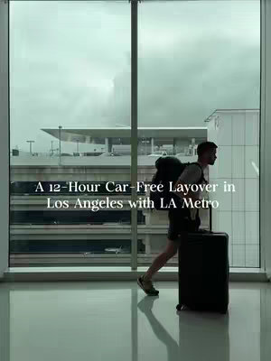 A person walking towards the right, silhouetted against a large window divided by vertical bars. The person carries a backpack and rolls a suitcase, suggesting travel. The background shows a cloudy sky and a glimpse of airport infrastructure.