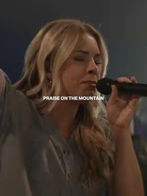 The cover image features a woman with blonde hair, facing towards the left, singing into a microphone. The text overlay reads "PRAISE ON THE MOUNTAIN". The background is dark, suggesting a stage or performance setting.