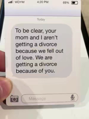 The image shows a screenshot of a text message on a smartphone. The background of the phone is white with slight shading. The time displayed is 4:20 PM, and the battery level is 69%. The text bubble has the words "Today" at the top. The text of the message fills most of the screen - white text against a gray background - reads: "To be clear, your mom and I aren't getting a divorce because we fell out of love. We are getting a divorce because of you." At the bottom is the 'message' text field. The hand of the user is slightly visible on left side of the frame, holding the phone.