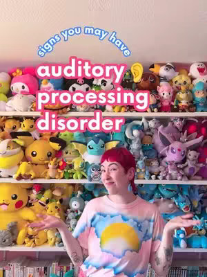 A person with red hair and a pink t-shirt stands in front of shelves packed with colorful stuffed animals. Text overlays at the top say "signs you may have auditory processing disorder."