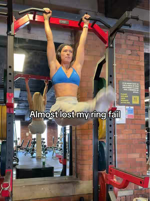 The cover image shows a woman hanging upside down from a red squat rack at a gym. She is wearing a blue sports bra and light-colored pants. The text overlay says "Almost lost my ring fail". In the background is a blurred reflection, brick walls and gym equipment.