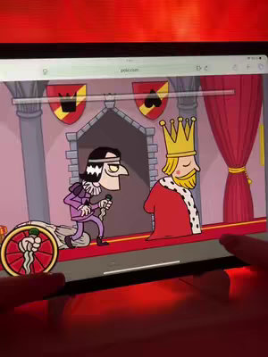 An iPad screen displays a cartoon scene from a game. The scene shows two cartoon characters: a king with a crown and a man with a dark mustache and a microphone, in front of a castle backdrop. Hands are visible at the bottom, holding the iPad.