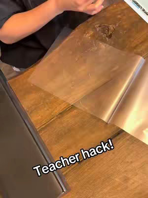 The cover image shows a person's hands, their arms in a black shirt, working on a wooden surface. Transparent, thin plastic sheets are spread across the surface, possibly for an activity or project.