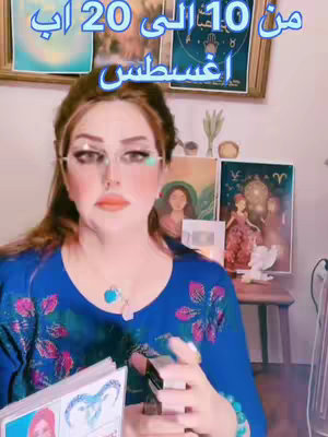 A woman with long brown hair is wearing glasses and a blue top. She is holding a tarot deck and multiple pictures are behind her. Text is overlayed at the top of the image.