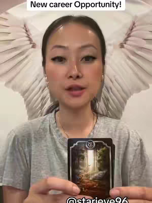 A woman with fair skin, dark hair, and prominent eye makeup is centered in the frame, holding two tarot cards. She is wearing a gray t-shirt and a simple necklace. Behind her, a mirrored wing-like shape appears, creating a halo effect. The text "New career opportunity!" arches above her head against a stark white background.