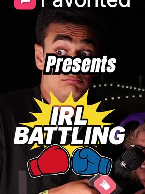 The cover image shows a man with a surprised expression, appearing to be in the foreground, with text overlays. Behind him is a darker setting with some blurred background elements, suggesting a live event or performance venue. The man has dark hair and is wearing a black shirt. A stylized text element reads “IRL BATTLING” in large, bold white letters with a yellow explosion effect behind it. Below the text are two boxing gloves, one red and one blue. The word "Favored" is on top side of the image.