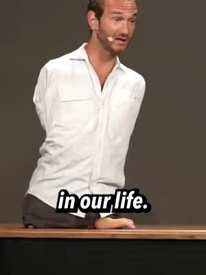 The image features a man, identified in the caption as Nick Vujicic, who is standing behind a table. He is wearing a white button-down shirt and pants. Text in a black box that says 'in our life.' is overlaid at the bottom of the image.
