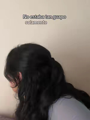 A selfie style shot focusing on the back of a woman's head and hair. The woman's face is slightly visible on the side, looking to the left. The background consists of a light-colored wall. Text overlay at the top reads: "No estaba tan guapo solamente".