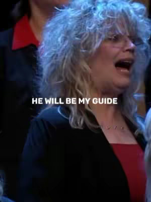 A woman with silver hair is singing into a microphone. Text overlayed on the image highlights the phrase "He will be my guide".