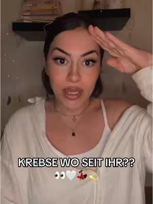 A woman with dark hair and makeup looks directly at the camera, her right hand raised near her forehead as if saluting. Text overlayed at the bottom reads 'KREBSE WO SEIT IHR??' along with some emojis.