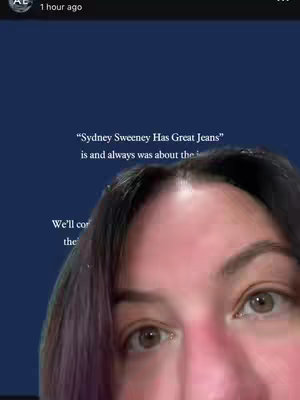 A selfie-style video cover with a close-up view of a person's face, focusing on their eyes and forehead. The top half of the face is visible, with dark hair and some purple highlights framing the forehead. Text overlays are positioned to the side, and the background is a flat, dark blue color.
