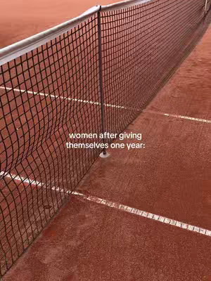 The cover image shows a close-up perspective of a tennis net stretching across the frame against a red clay court background. The net itself is the central element, its dark mesh creating a strong contrast against the terracotta color of the court. Parts of the net are curved. White lines are partly visible on the court's surface, indicating the boundaries of the play area. The image is well-lit and focuses on the textures and colors of the environment.