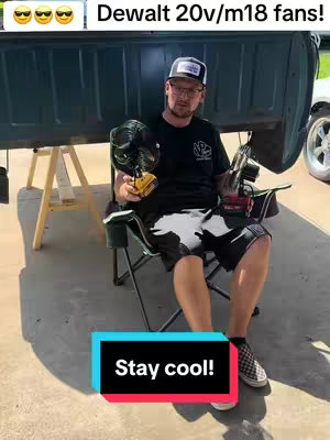 A man sits in a camping chair holding two fans showcasing them. A red and black sticker overlay shows the words Stay cool!