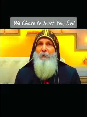 The image shows a close-up of an older man with a long white beard, wearing a black robe and a golden and black hood. A text overlay in a gray rectangular box at the top says, "We Chose to Trust You, God."