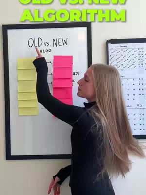 A woman points to a whiteboard with the headline: Old vs New Algorithm. The woman has blonde hair and is wearing a black top. The setup is in an office or home setting.