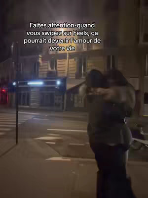 The image captures a night scene with two figures embracing on a city street. The composition centers on the couple, their forms silhouetted against the backdrop of buildings and streetlights. Text is overlaid, floating above the couple, written in a bold font and offering context.