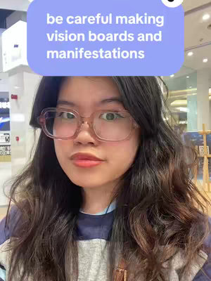 The cover image features a woman in a selfie pose. She is wearing glasses and looking directly towards the camera. A text overlay in a speech bubble at the top reads, “be careful making vision boards and manifestations”. The background shows a retail setting.
