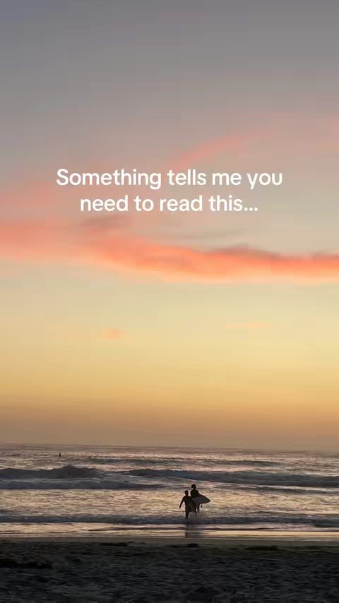 A scenic landscape at sunset or sunrise, with a beach in the foreground and the ocean with waves in the midground. Two silhouetted figures with surfboards are walking into the water. The sky is a blend of orange and pink hues, indicating either a sunrise or sunset. Text overlayed on the image reads "Something tells me you need to read this..."
