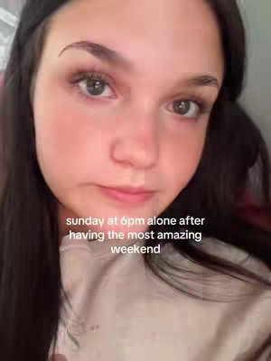 A selfie of a woman with dark hair, fair skin, and visible eye makeup. The background is blurred. Text overlayed at the bottom describes the time and context.