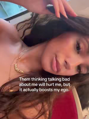 A selfie-style shot featuring a woman with long, dark hair, looking towards the camera with a slight smile. She is wearing a gold necklace. Overlayed text provides a self-assured statement.