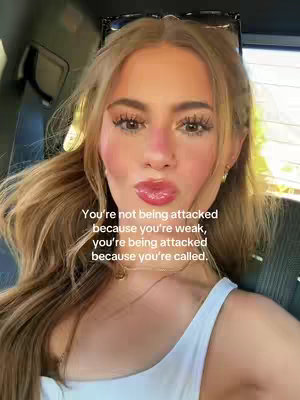 A selfie-style shot featuring a young woman with fair skin, long blonde hair, and light makeup. Additional features include sunglasses, a white tank top, and a gold necklace. The text overlay sits over her face, it has a casual setting which appears to be inside a vehicle with a window on the right side with a blurred background.