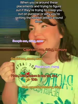 A woman in a light green t-shirt holds a mug, with several astrological signs in text overlaid on the image, against a background that appears to be a window. The woman is smiling and looking towards the right side of the frame.