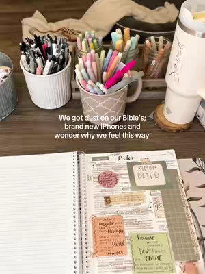 A close-up shot of an open Bible with notes and colorful pens scattered around. The Bible is open to a page with handwritten notes and highlighted text. Various pens in different colors are arranged in cups and containers in the background. There is a casual, inviting aesthetic.