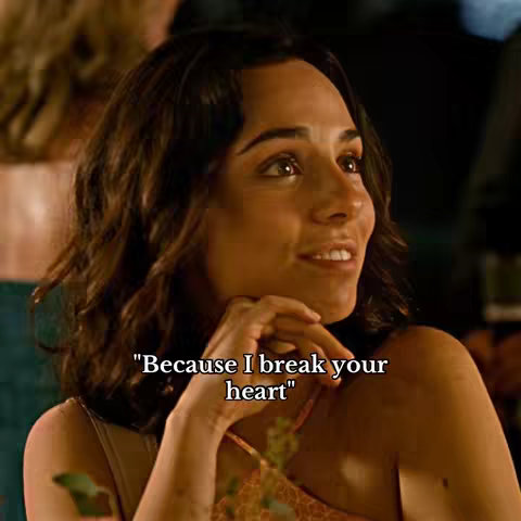 A woman with long, wavy brown hair looks up and to the side, a slight smile on her face. The background is blurred, suggesting an indoor setting. White text overlayed says, "Because I break your heart."