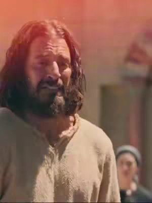 The cover image features a man with long hair and a beard, likely portraying Jesus Christ, looking towards the side with a contemplative expression. The background suggests an outdoor setting with other indistinct figures present, with an overlay of a reddish hue across the upper part of the frame.