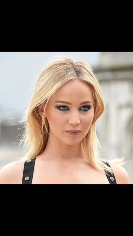 The cover image is a close-up portrait of a woman with blonde hair, light skin, and dramatic makeup. The background is out of focus, suggesting an outdoor setting, possibly a building facade. The woman has a neutral expression, with her gaze directed towards the camera.