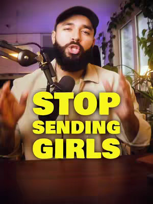 A man with a beard is centered in the frame, gesturing with his hands towards the viewer. Overlayed on top of him are large, yellow, uppercase words that read, "STOP SENDING GIRLS". The background is softly blurred, with warm lighting from a lamp to the left and greenery suggesting an indoor setting.