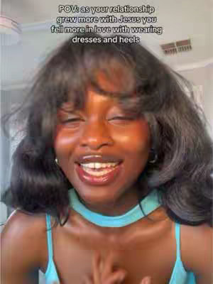 A close-up of a smiling Black woman with dark hair and blue attire, likely a top and a choker-style necklace. She's looking up with eyes closed, appearing joyous. Text is overlaid, explaining that as the relationship with Jesus grew, she fell more in love with dresses and heels. The background is indistinct.