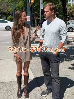 A woman in a blazer and boots interviews a man on a city street with a sign that says '$250k - $350k a year'.