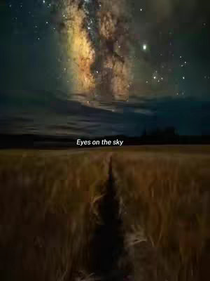 A vast landscape is shown under a night sky filled with stars, featuring a bright Milky Way. In the foreground, there's a field with a path running through it, leading into the distance. Text overlayed states 'Eyes on the sky'.