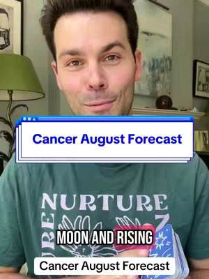 A man with short brown hair is looking at the camera with a slight smile. He is wearing a green t-shirt that says 'NURTURE' in white text. There are three white boxes overlaid on each other with text; The top one says 'Cancer August Forecast', the middle one says 'MOON AND RISING', and the bottom one says 'Cancer August Forecast'. He is holding a deck of tarot cards.