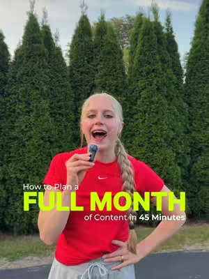 A woman with blonde hair in a ponytail is holding a microphone and looking at the camera. She is wearing a red shirt with a Nike logo on it. The background consists of tall green bushes. White text overlays the image: 'How to Plan a FULL MONTH of Content in 45 Minutes'.