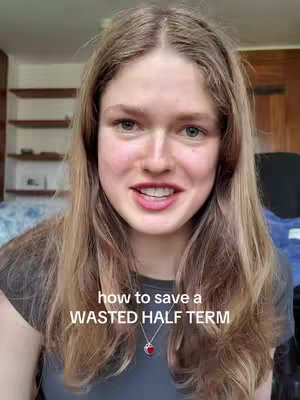 A young woman with long, light brown hair smiles directly at the camera. She wears a gray t-shirt with a silver necklace. Behind her, a room with wooden shelves on the wall are visible. Text overlay on image: "how to save a WASTED HALF TERM"