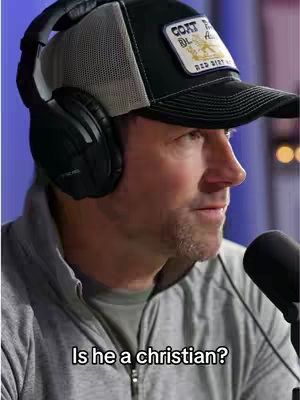 A man wearing a baseball cap, headphones, and a grey jacket is looking to the right, with a microphone in the lower right. White text at the bottom reads: 'Is he a christian?'