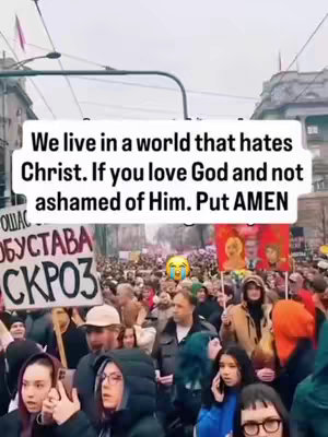 A crowd of people walking down a street is shown, with a sign in the foreground that has text in a language other than English. A text overlay is on the image, and a yellow crying face emoji is added over the people.
