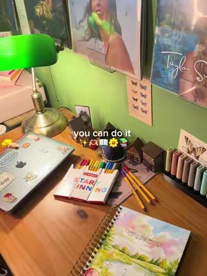 A top-down view of a wooden desk organized for studying. On the desk are school supplies, a laptop, and framed pictures. The text 'you can do it' is overlaid on the image in the center.