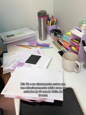 A slightly overhead shot of a white desk, covered with study materials such as notebooks, papers, pens, and a coffee mug. The background consists of a white wall. Text is overlaid, using a white sans-serif font with a black background.