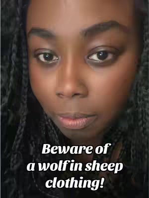 A close-up shot featuring a black woman looking directly at the camera. She has dark braids and neutral makeup. Text overlayed is "Beware of a wolf in sheep clothing!"