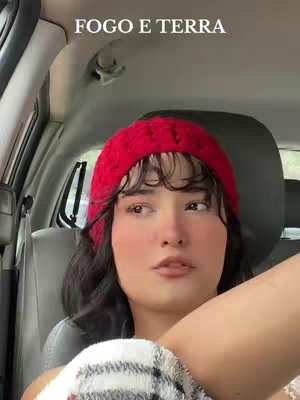 A woman in a red knit cap in a car looking up at the camera with an added overlay of white text at the top of the image.