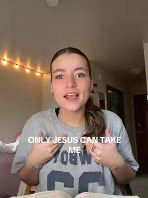 A young woman in a light grey t-shirt with the words 'ONLY JESUS CAN TAKE ME' overlaid on the front. She is indoors with a neutral background.